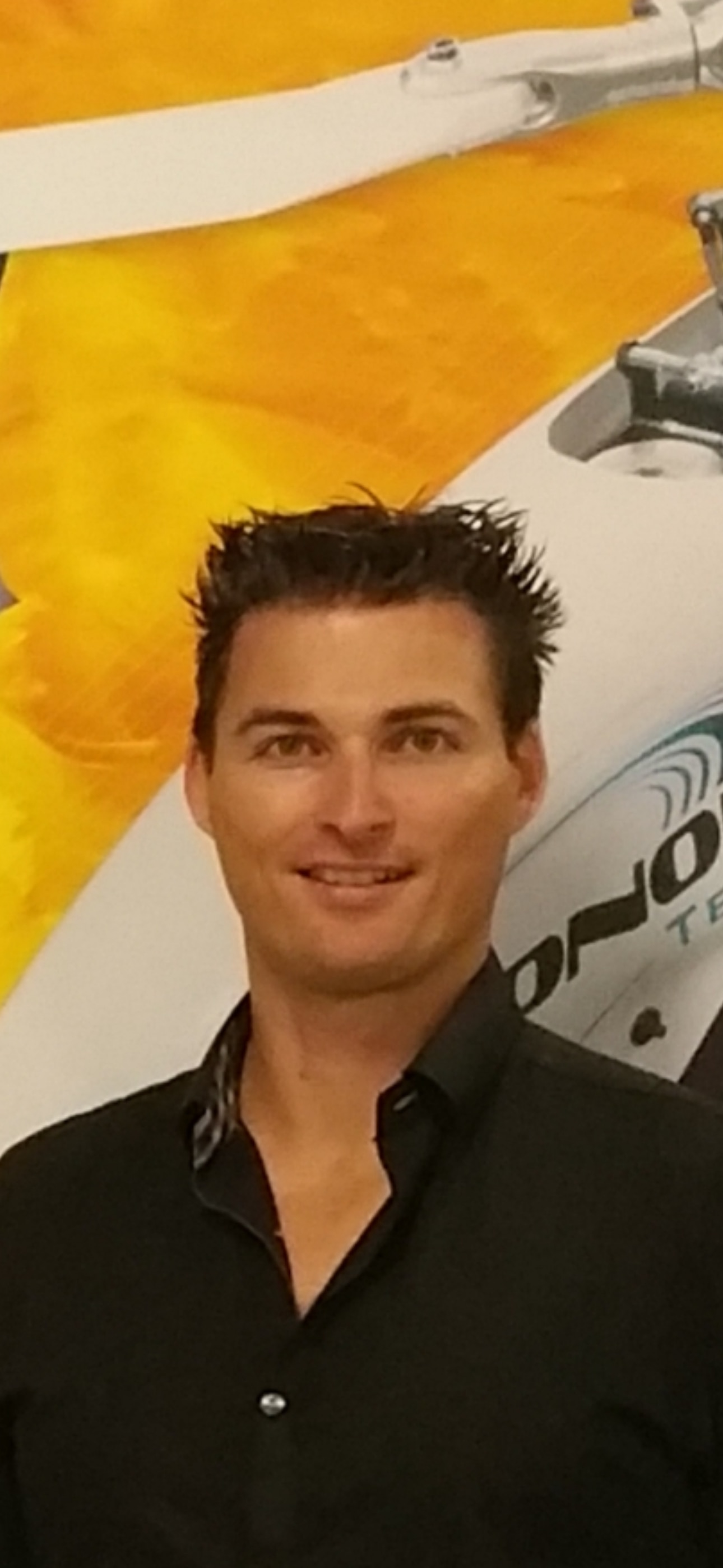 Mr. Brown, wearing a black collared shirt, smiles at the camera.