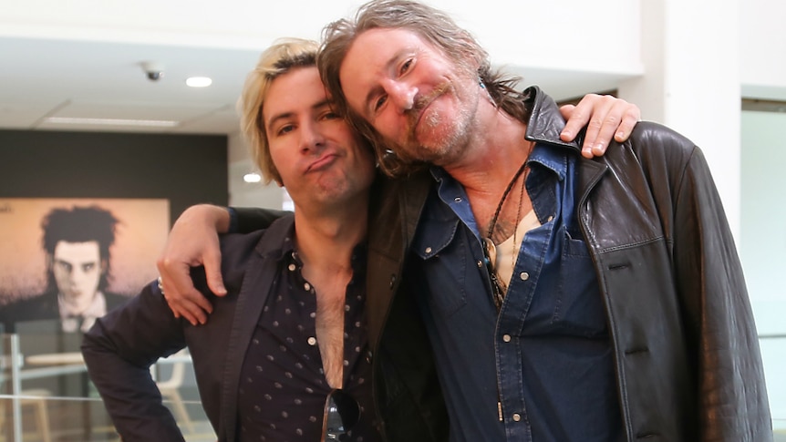 You Am I bandmates Davey Lane and Tim Rogers stand with their arms around each other's shoulders