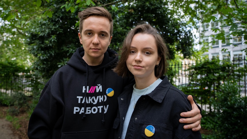 A boy wearing a Ukrainian jumper puts his arms around a woman wearing a denim jacket.