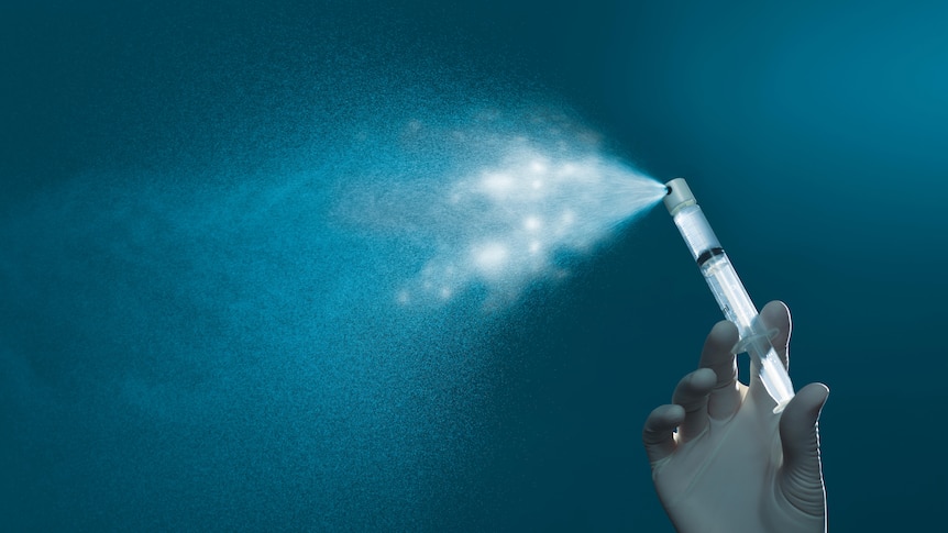 a gloved hand spraying fluid against a dark blue background