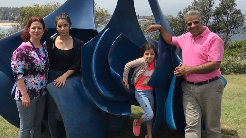 Jila Solaimani, Hasti Rostami, Hedieh Rostami and Reza Rostami, left to right, stand in front of a blue sculpture.