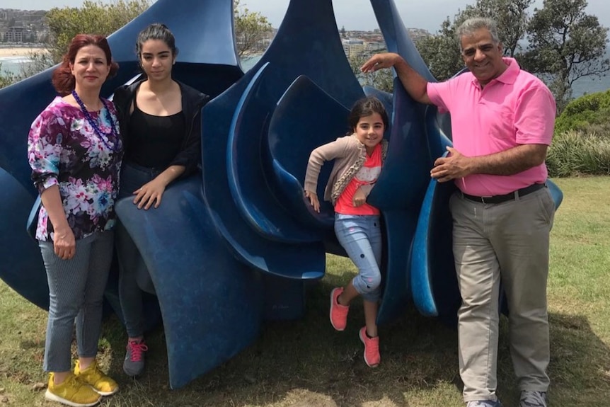 Jila Solaimani, Hasti Rostami, Hedieh Rostami and Reza Rostami, left to right, stand in front of a blue sculpture.