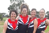 Four women in AFL gear gather for a photo.
