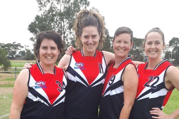 Four women in AFL gear gather for a photo.