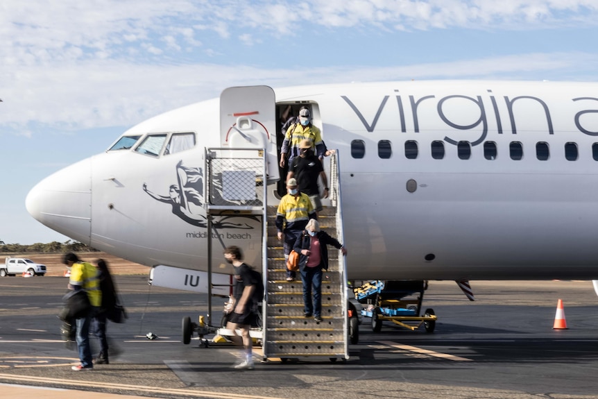 Passengers disembark a Virgin Australia flight by walking down stairs onto tarmac.  