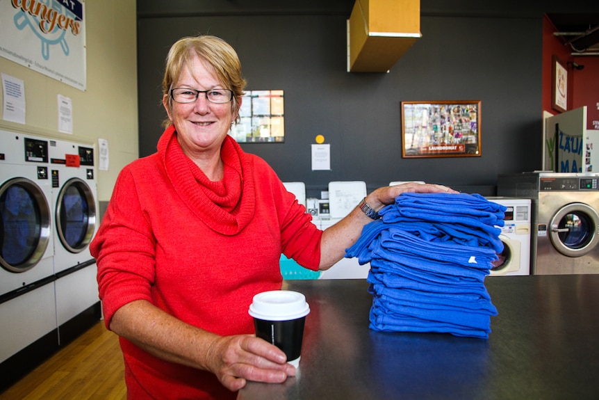 Coordinating Supervisor of Laundry Mates, Dianne Smith with a pile of blue towels.