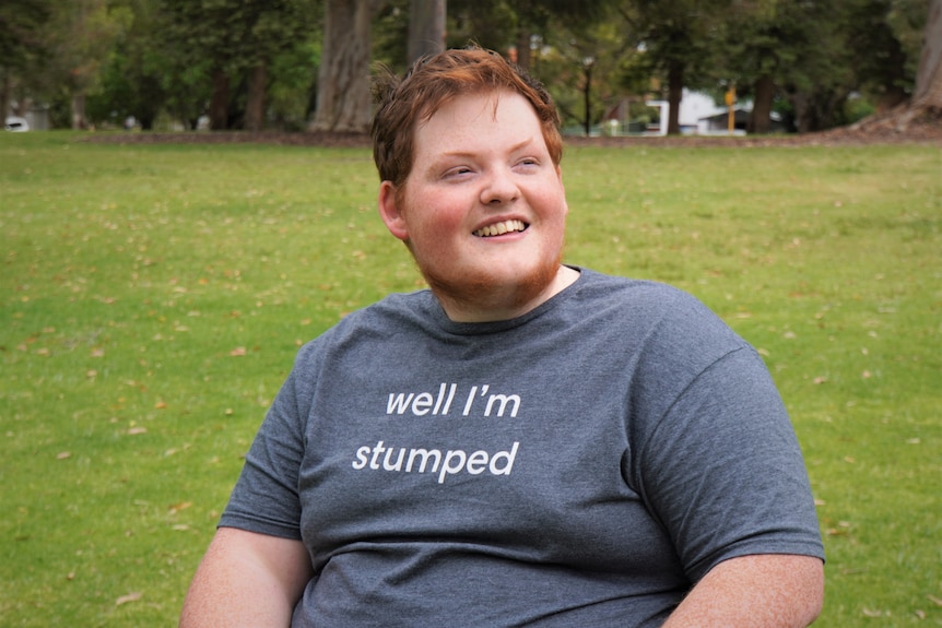 A mid-shot of Angus who is smiling and looking to the side. His t-shirt says 'well I'm stumped' 