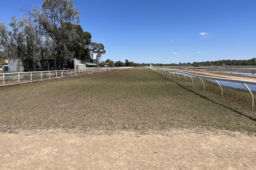 A dried out horse racing track with flood waters on the right side
