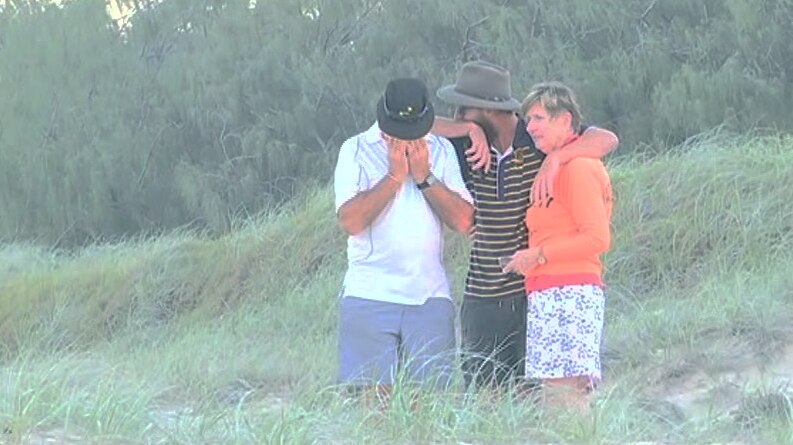 Emotional family console each other on beach.