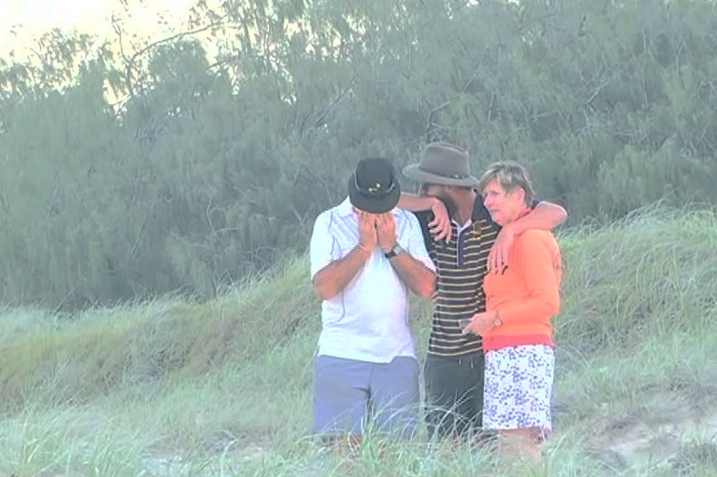 Emotional family console each other on beach.