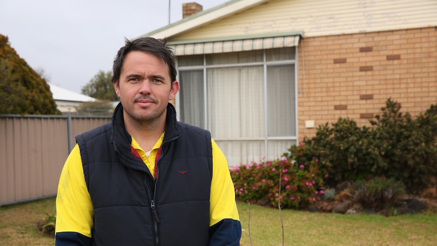 A man stands in front of a brick rental property.