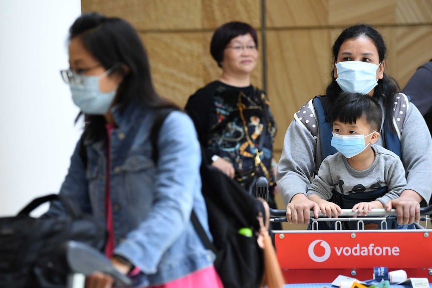 Travellers wearing facemasks leave Sydney airport