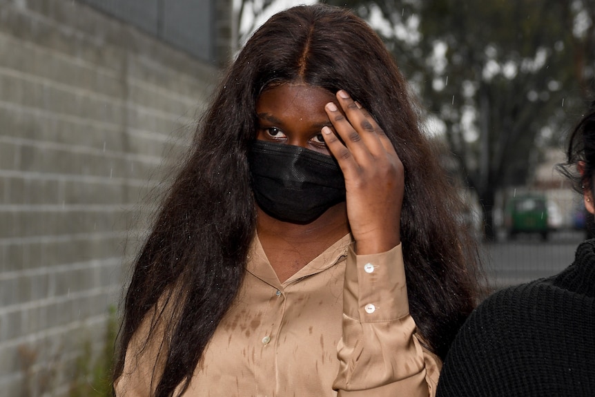 Josephine Lado holds up her hand outside court