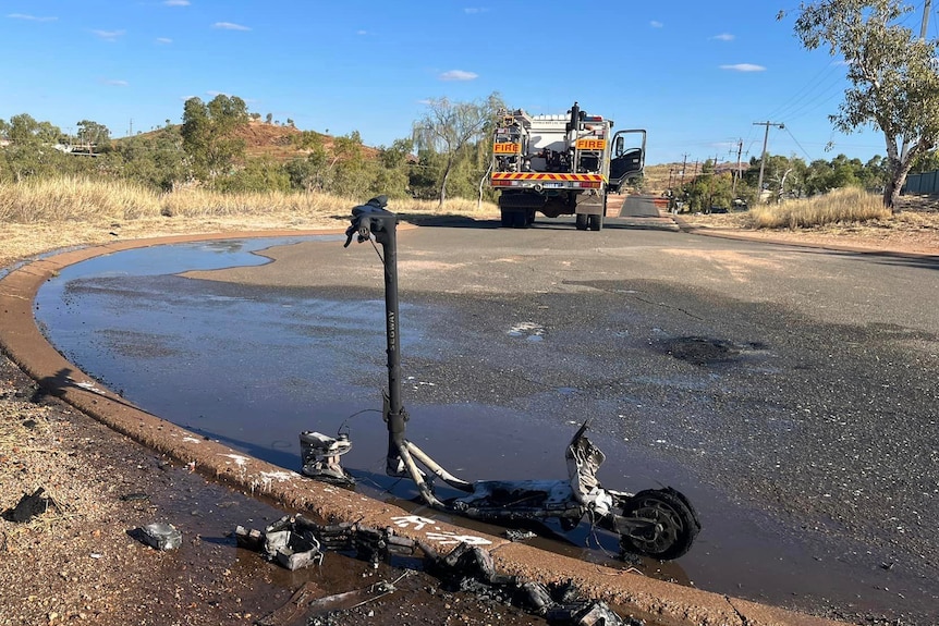 An e-scooter smouldering after a fire on a road in Marble Bar