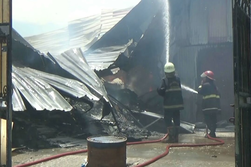 Firefighters douse a factory fire with water.