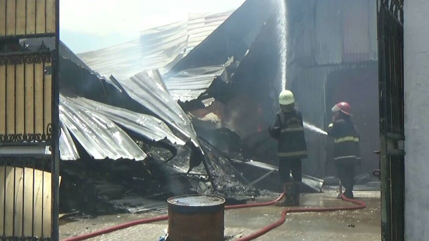 Firefighters douse a factory fire with water.