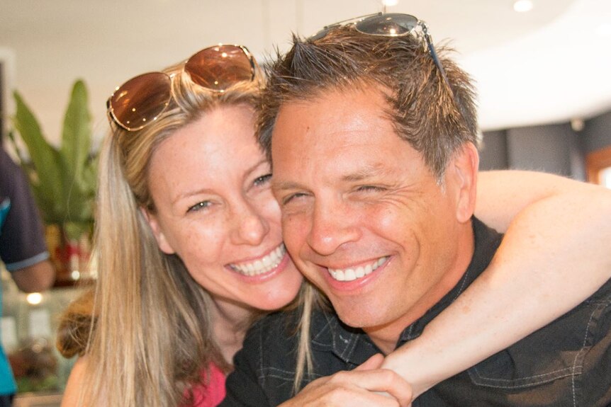 A man and woman with big smiles on their face pose for photo with arm around each other