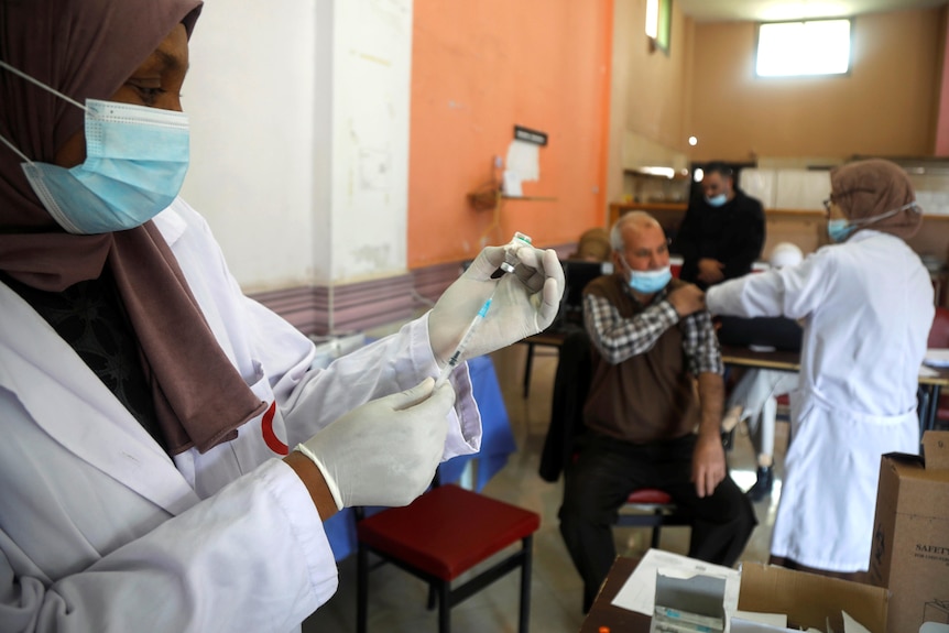 A Palestinian health worker prepares Sinopharm vaccine against the coronavirus disease