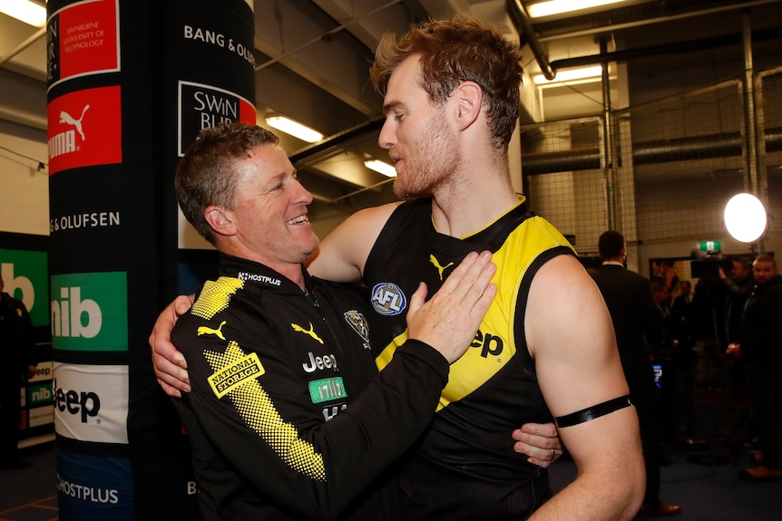 AFL player and coaching hugging after winning a match