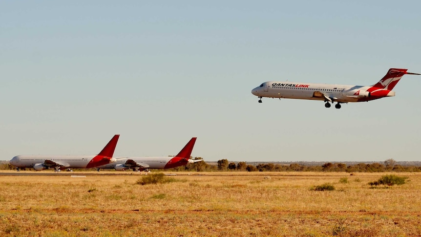 A Qantas plane landing on desert runway.