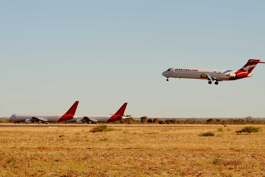 A Qantas plane landing on desert runway.