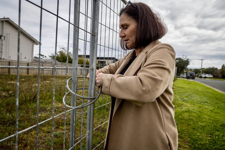 A woman unlocking a metal fence