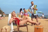 Kylie Minogue sits on a chair in a red swimsuit on Sandringham Beach.