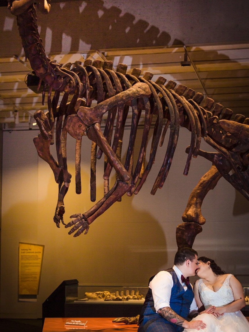 Couple sitting under a dinosaur skeleton