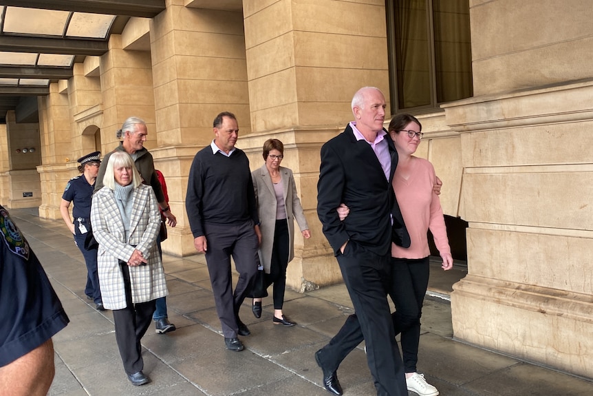 Un groupe de personnes marche le long d'un sentier à l'extérieur d'un grand palais de justice