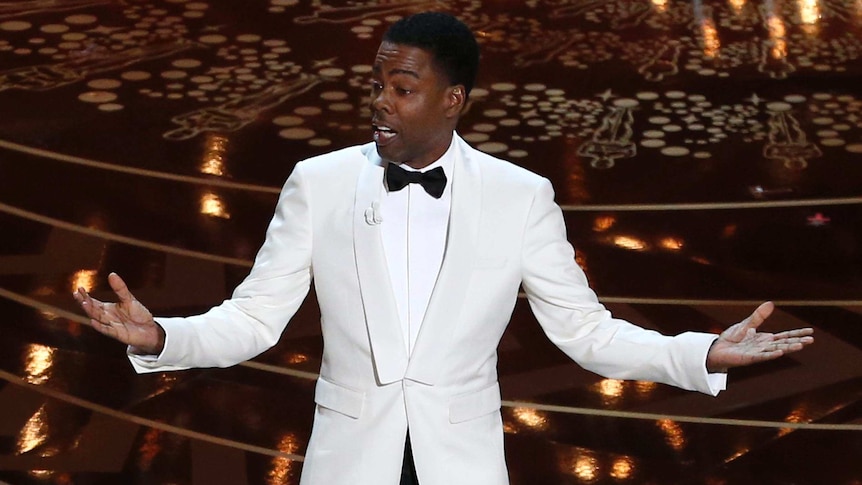 Elevated view of Chris Rock gesturing with arms outstretched as he opens the Oscars.