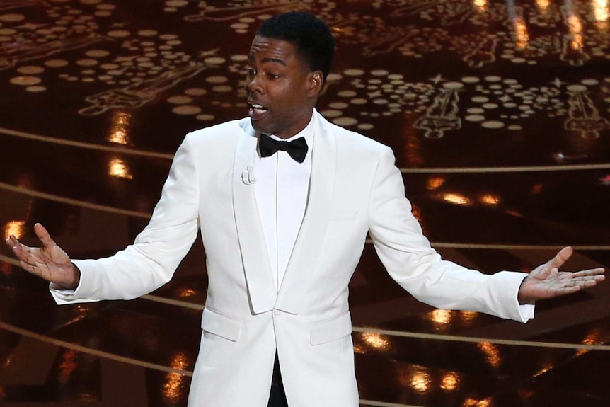 Elevated view of Chris Rock gesturing with arms outstretched as he opens the Oscars.