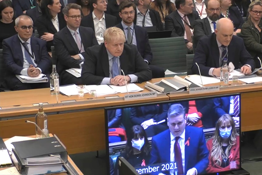 Johnson sits slumped forward as a screen below him shows Keir Starmer