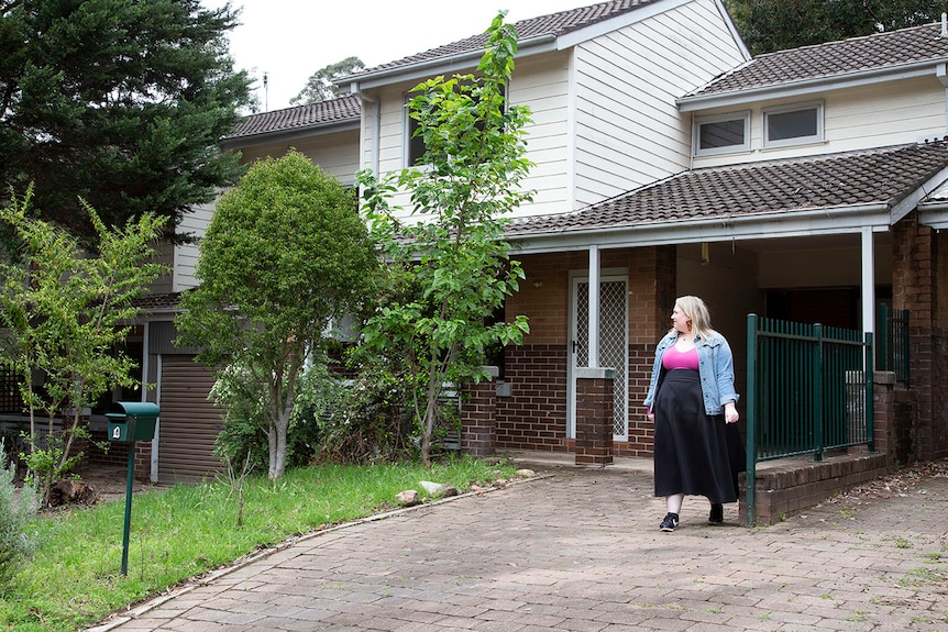 A woman wearing pink and black looks at the exterior of a unit