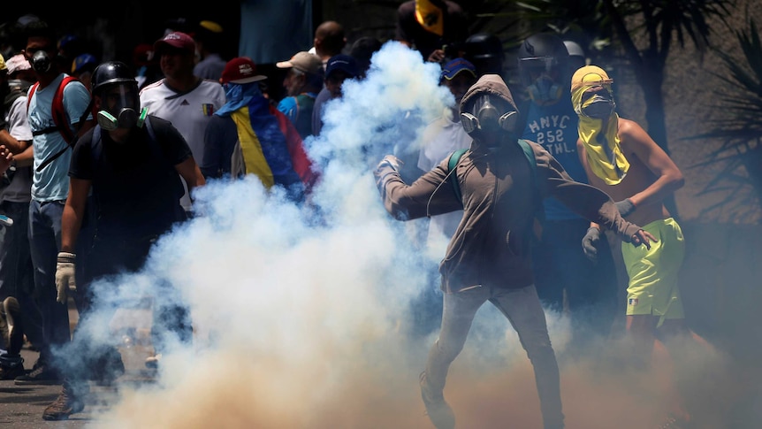 Demonstrators throw objects as they are surrounded by smoke.