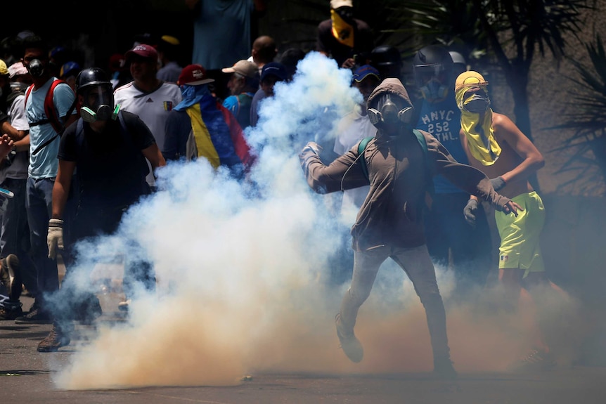 Demonstrators throw objects as they are surrounded by smoke.