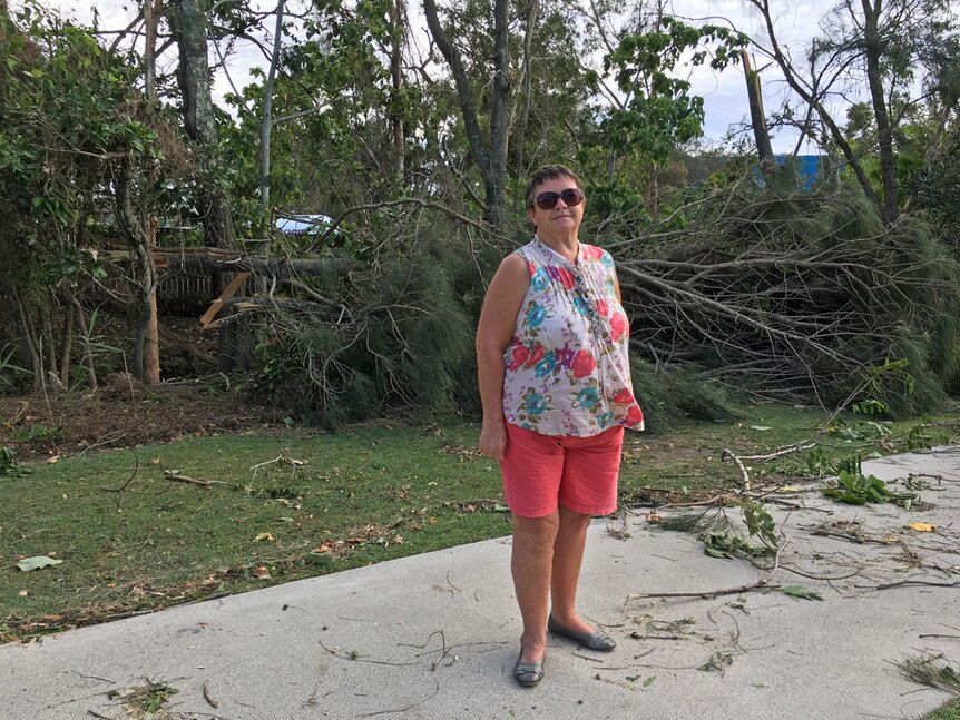 Woman standing in front of downed trees.