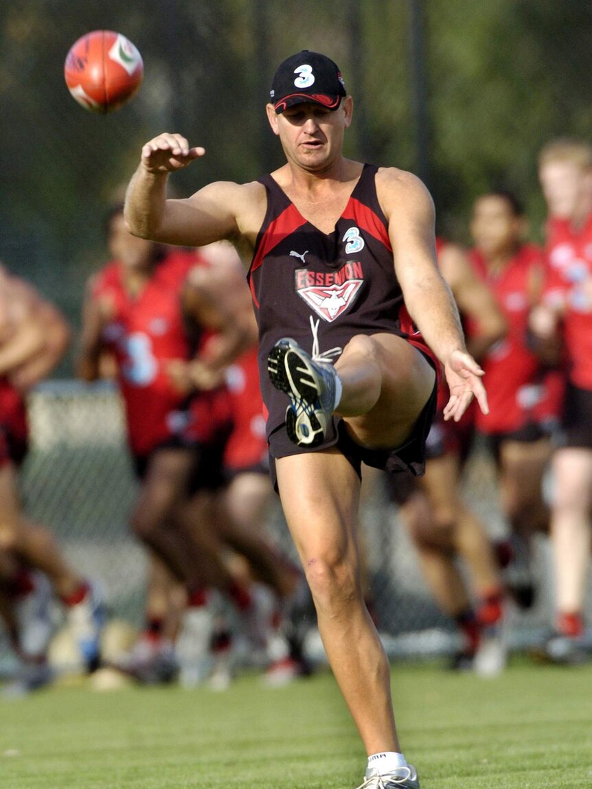 John Barnes wears a cap as he kicks a ball during Essendon training at Windy Hill