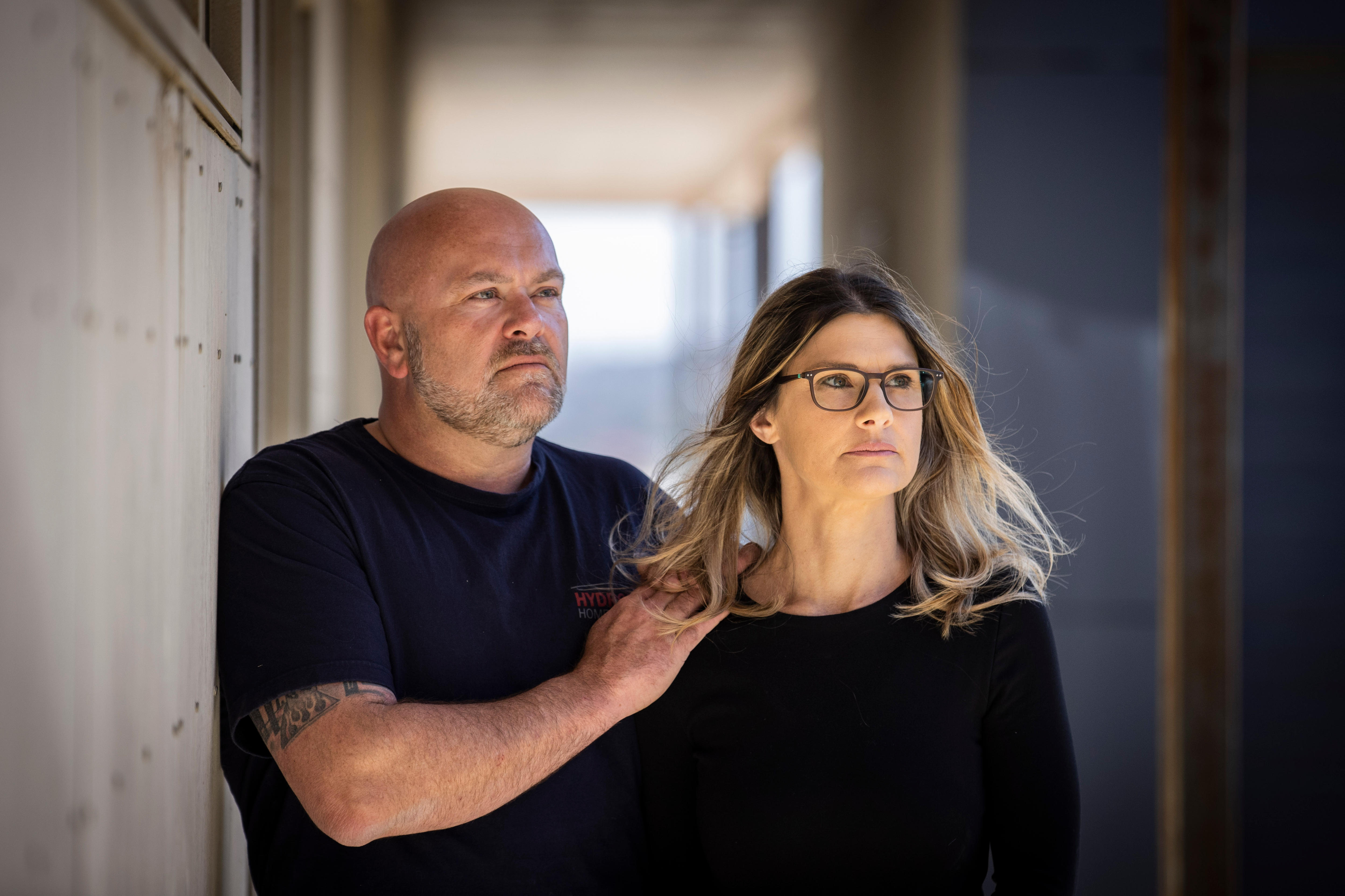 A man an woman look at the bare walls of their unfinished home.