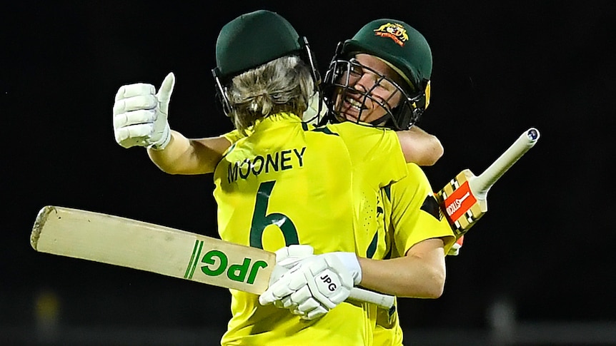 Two Australian female cricketers embrace after they secured victory against India.
