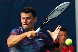 Bernard Tomic plays a forehand against Gilles Muller.