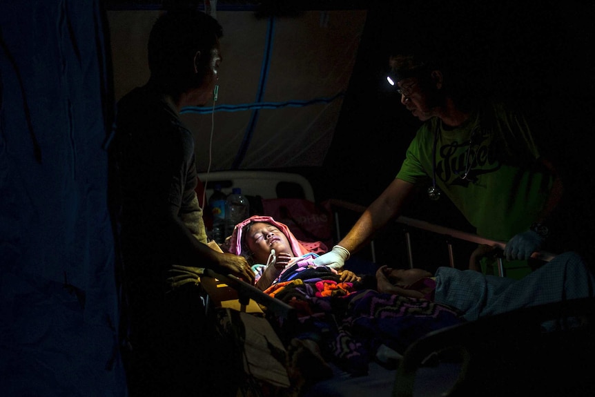 A doctor comforts a child injured in an earthquake at a makeshift hospital