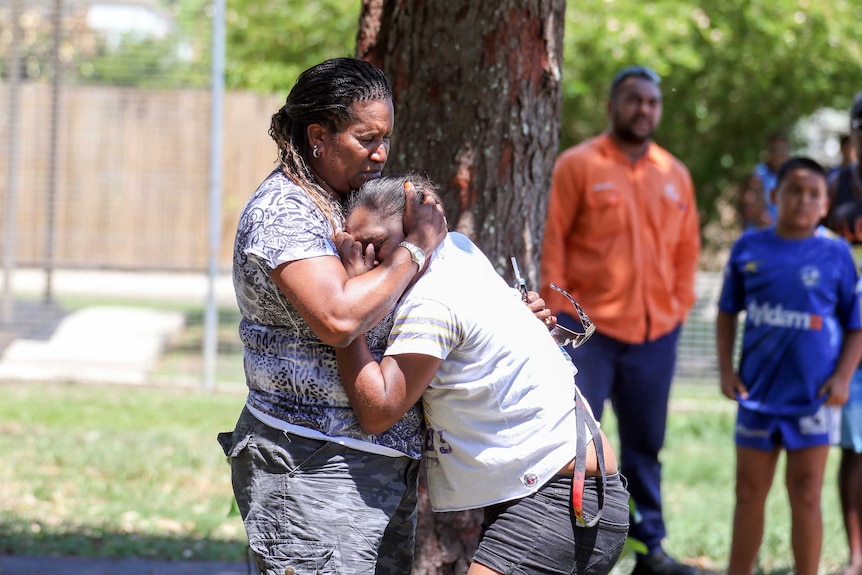 People believed to be relatives of the victims grieve outside the Manoora home.