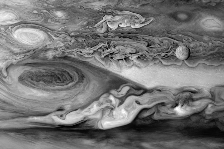 Europa, one of Jupiter's moons, can be seen on the right hand side of this image, drifting past the Great Red Spot