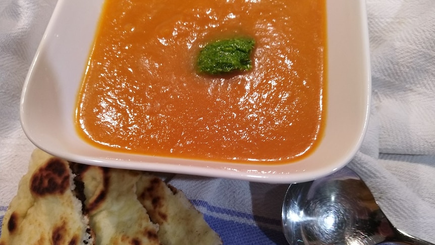 A bowl of soup, with flatbread on the side