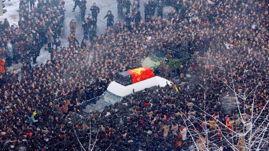North Koreans surround a hearse carrying the coffin of late North Korean leader Kim Jong-il
