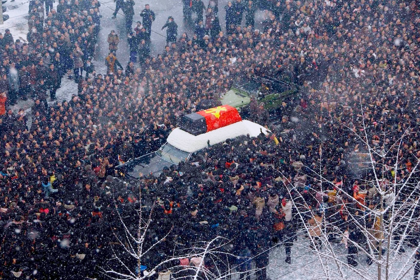 North Koreans surround a hearse carrying the coffin of late North Korean leader Kim Jong-il