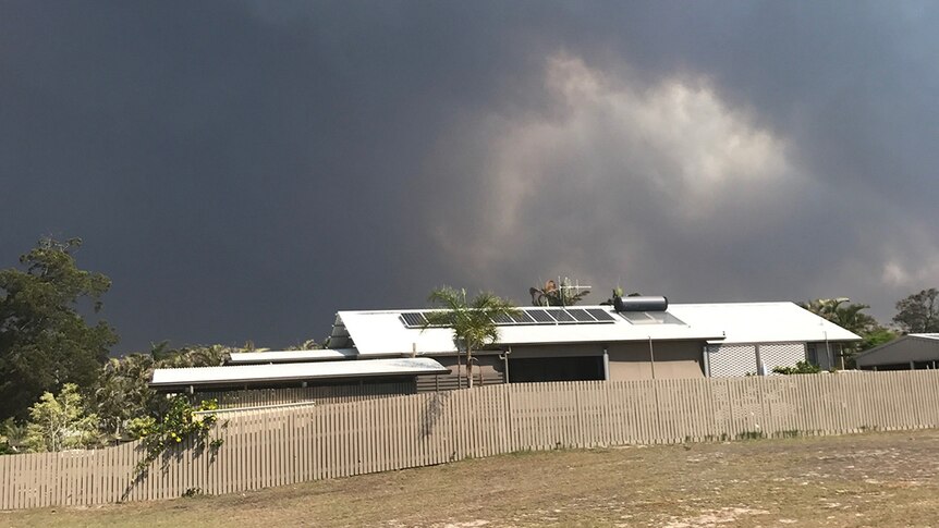 Huge black smoke plume from bushfires looms behind house at Woodgate.