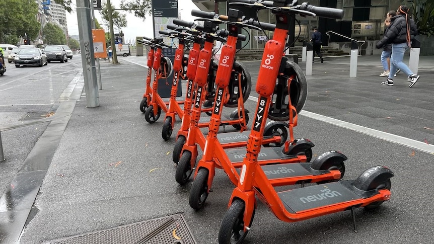Orange scooters parked on a CBD street on a grey overcast day.