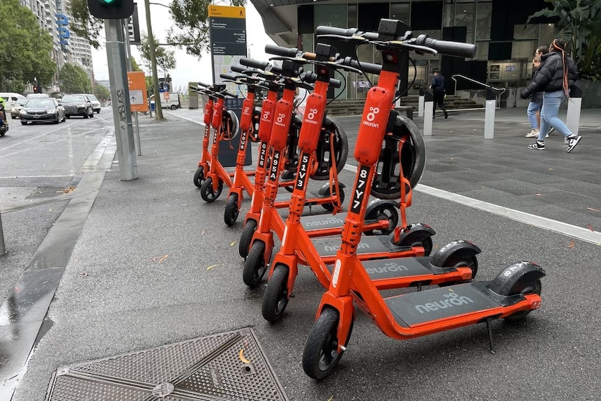 Orange scooters parked on a CBD street on a grey overcast day.