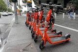 Orange scooters parked on a CBD street on a grey overcast day.